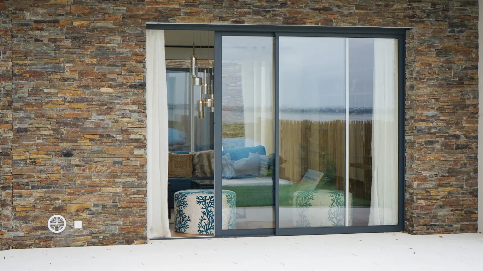 Fenêtre coulissante aluminium anthracite installée sur façade en pierre à Valence, offrant une grande ouverture lumineuse vers l’extérieur